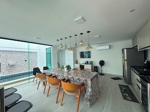 A modern kitchen with a dining area, large windows, and a view of a patterned wall outside. - House in a gated community in Lençóis Maranhenses with a swimming pool and 4 suites. (Barreirinhas)