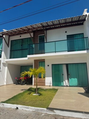 A two-story building with a flat roof, large windows, and a covered entrance area. - House in a gated community in Lençóis Maranhenses with a swimming pool and 4 suites. (Barreirinhas)