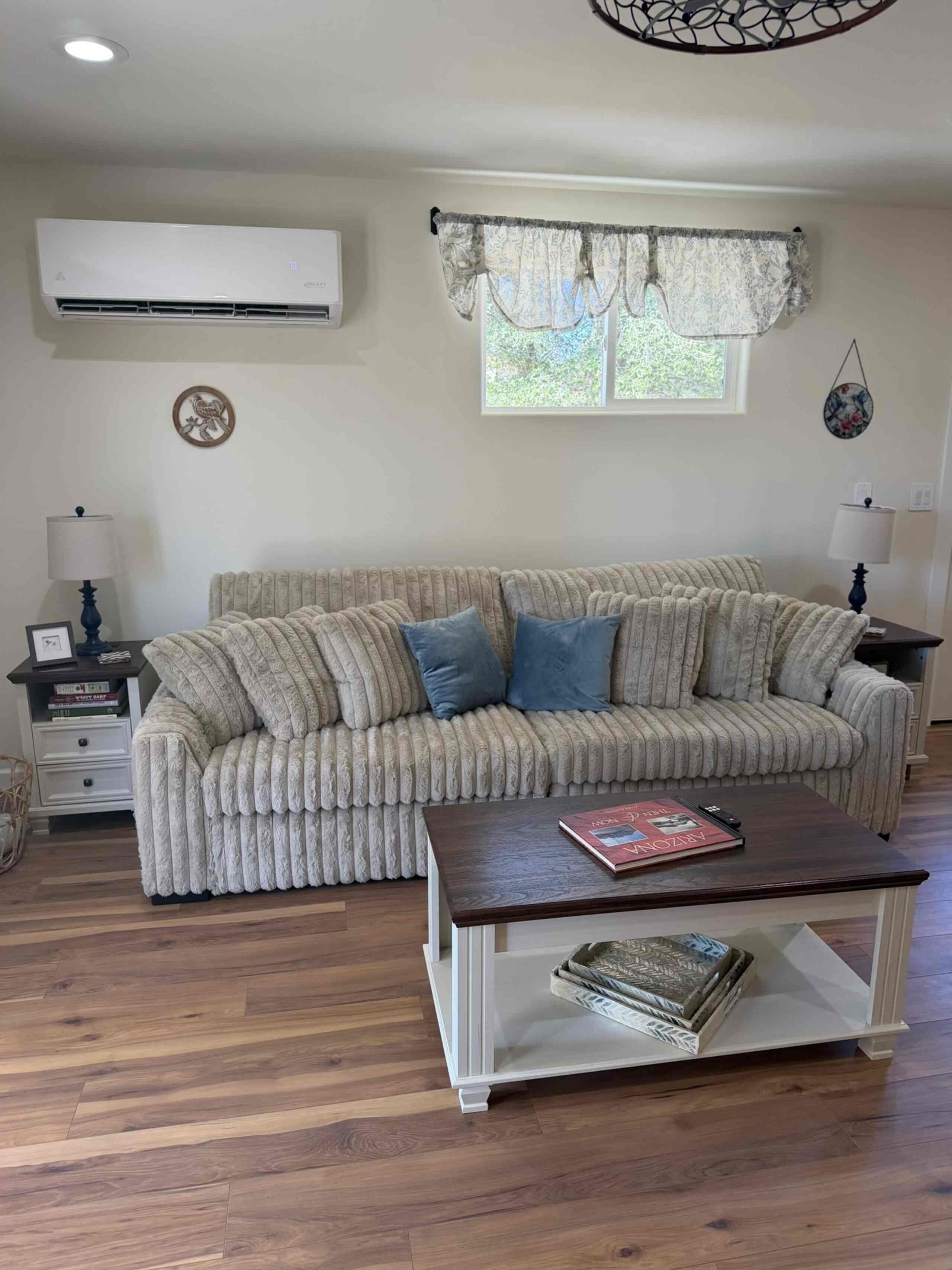 A living room with a patterned sofa, a coffee table, and a window with curtains.