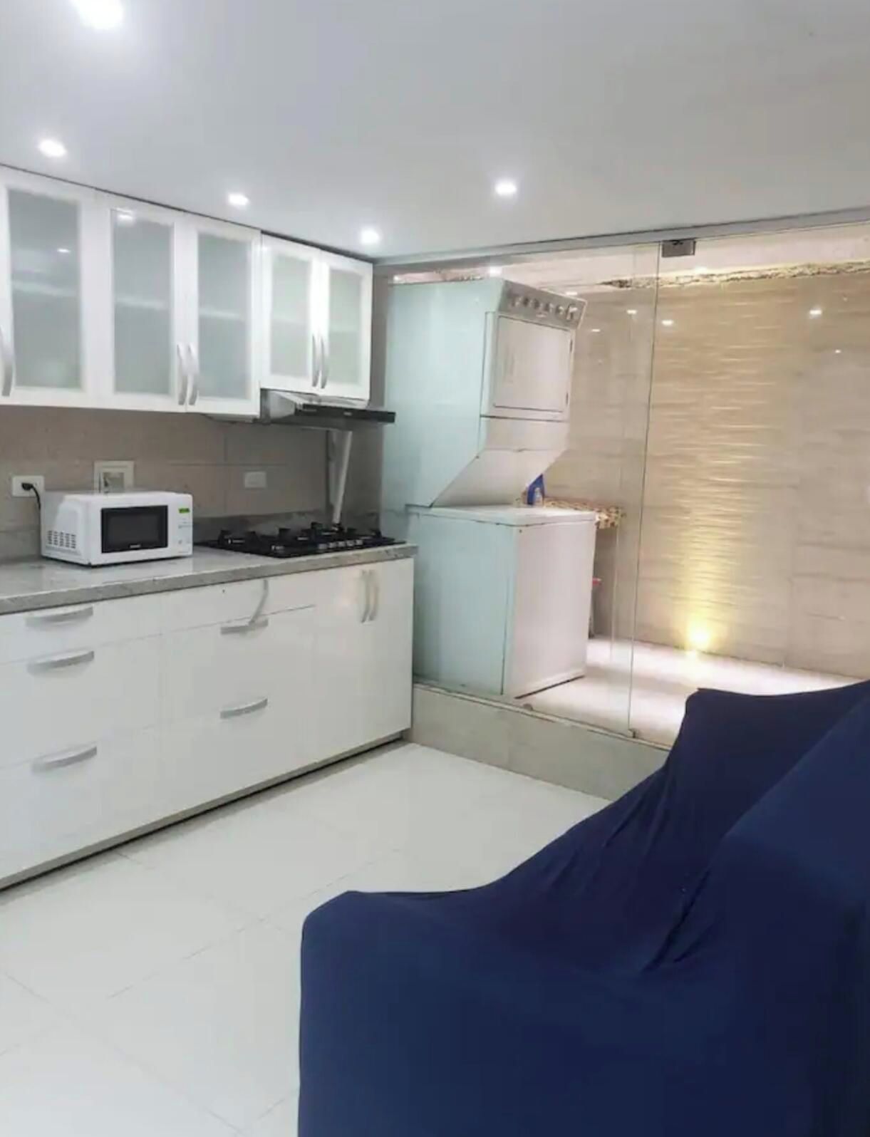 Cozinha compacta com armários brancos, micro-ondas, fogão e geladeira.