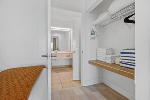 Une salle de bain avec un plancher en bois, un porte-serviettes où sont pliées des serviettes, et un miroir au-dessus du lavabo.