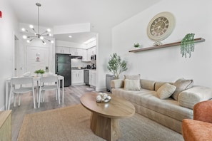Ein modernes Wohnzimmer mit Sofa, Couchtisch und Essbereich mit Stühlen.