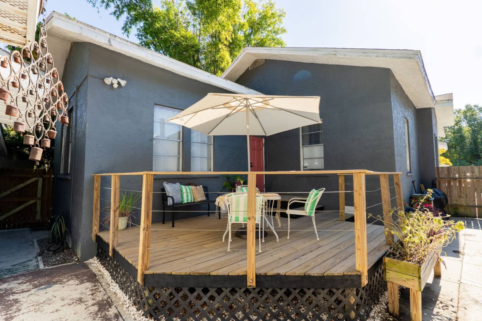 Terraza con mobiliario exterior y una sombrilla grande, rodeada por una valla de madera y un barandal de celosía.