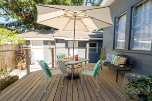 Eine Terrasse mit Tisch, Stühlen, einem großen Sonnenschirm und einer Bank.