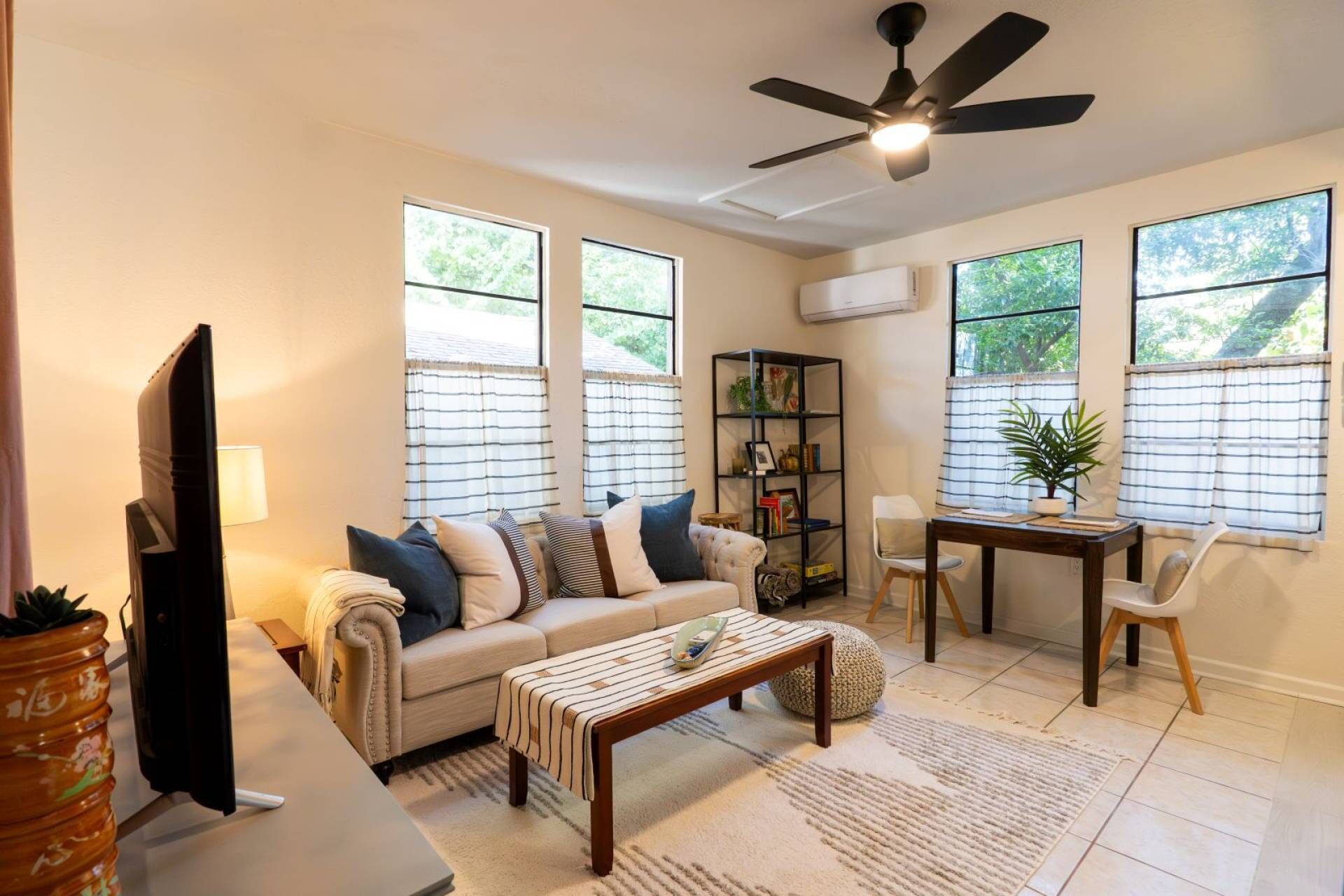 A living room with a sofa, coffee table, TV, and a ceiling fan.