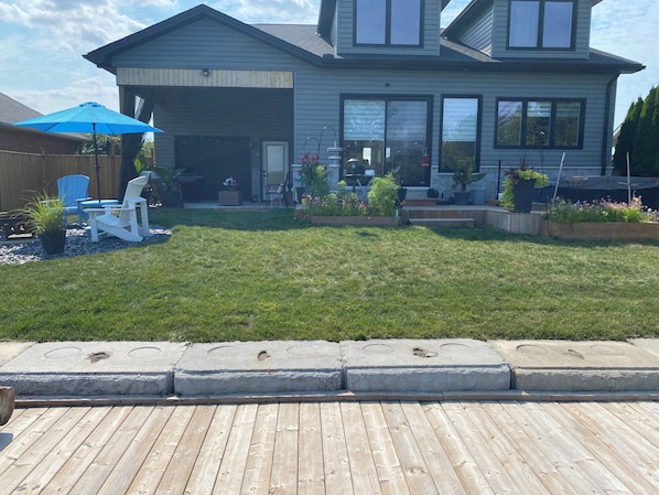 A residential property with a covered patio, a lawn, and a deck.