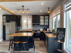 A modern kitchen with a central island, bar stools, and a chalkboard sign.