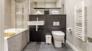 Een moderne badkamer met een douchecabine van glas, een wit toilet, een zwart kastje met spiegel en een handdoekhouder.
