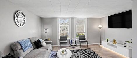 A modern living room with a grey sofa, a coffee table, and a patterned rug.