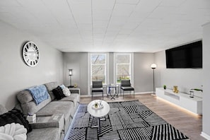 A modern living room with a grey sofa, a coffee table, and a patterned rug.