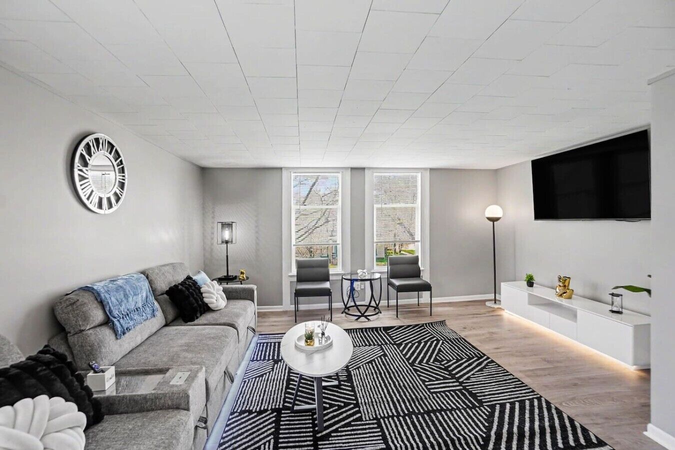 A modern living room with a grey sofa, a coffee table, and a patterned rug.