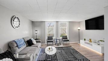 A modern living room with a grey sofa, a coffee table, and a patterned rug.