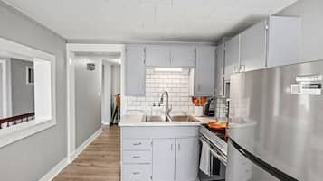 A modern kitchen with grey cabinets, a stainless steel refrigerator, and a tiled backsplash.