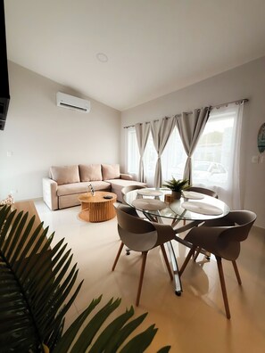 Ein modernes Wohnzimmer mit einer Couch, einem Glastisch mit Stühlen und einem Couchtisch.