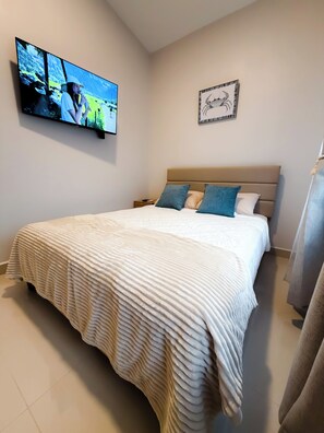 A bedroom with a bed, a television mounted on the wall, and a framed picture above the bed. - Brand New: Boutique House, Near LIR Airport & Best Beaches (Guanacaste Province)