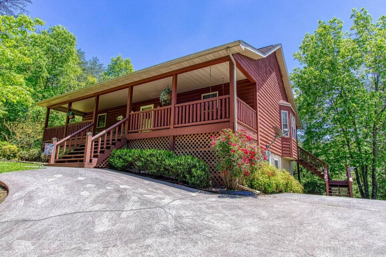 A two-story log cabin with a porch, a staircase, and a satellite dish.