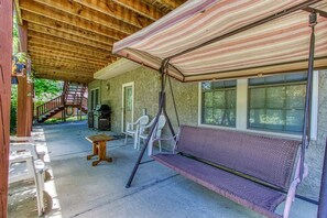 A covered outdoor area with a swing, a table, and chairs. - Bluebird`s Song 5BR, 3.5BA by HoneyBearCabins (Sevierville)