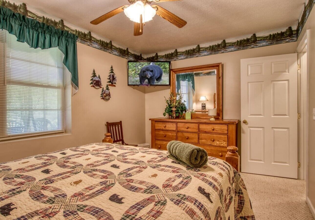 Un dormitorio con cama, cómoda, televisor y una puerta.