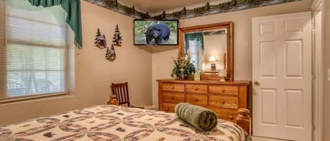 Un dormitorio con cama, cómoda, televisor y una puerta.
