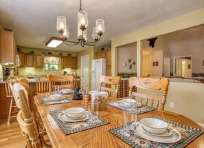 A dining area with a wooden table set for four, surrounded by wooden chairs. - Bluebird`s Song 5BR, 3.5BA by HoneyBearCabins (Sevierville)