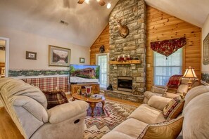 A cozy living room with a stone fireplace, comfortable seating, and a television. - Bluebird`s Song 5BR, 3.5BA by HoneyBearCabins (Sevierville)