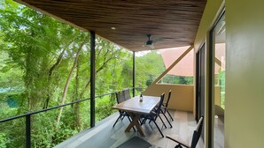 Un balcon avec une table et des chaises, donnant sur un paysage verdoyant et luxuriant.