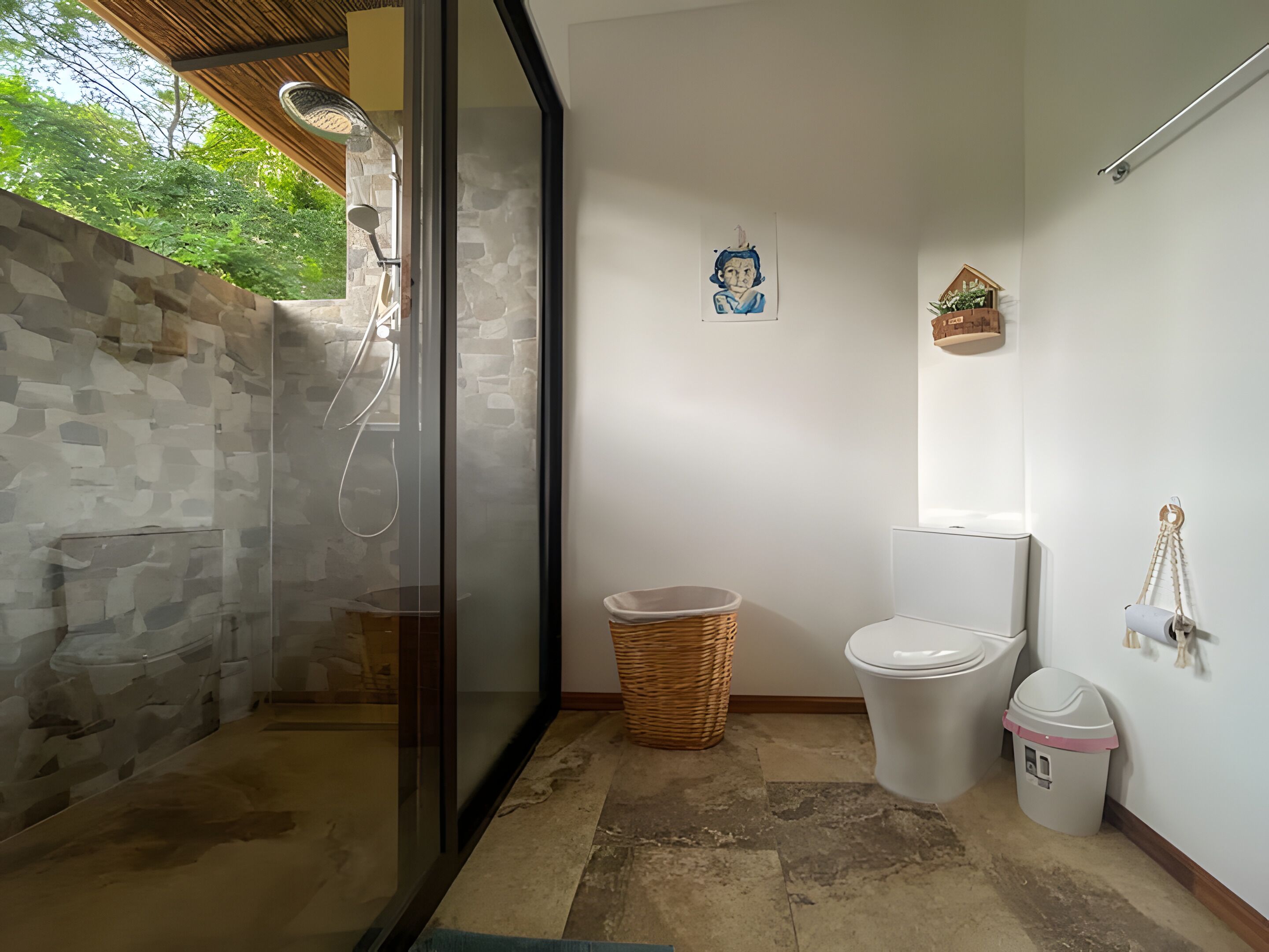 Un baño moderno con ducha envuelta en vidrio, un inodoro y una pequeña cesta de mimbre.