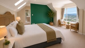 A hotel room with a large bed, a view of the city, and a green accent wall. - Sky Nova Villa False Bay Mountain & Ocean Views (Cape Town)