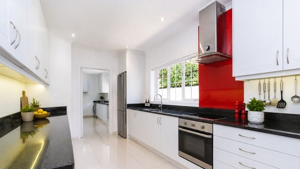 A modern kitchen with white cabinets, stainless steel appliances, and a black countertop. - Sky Nova Villa False Bay Mountain & Ocean Views (Cape Town)