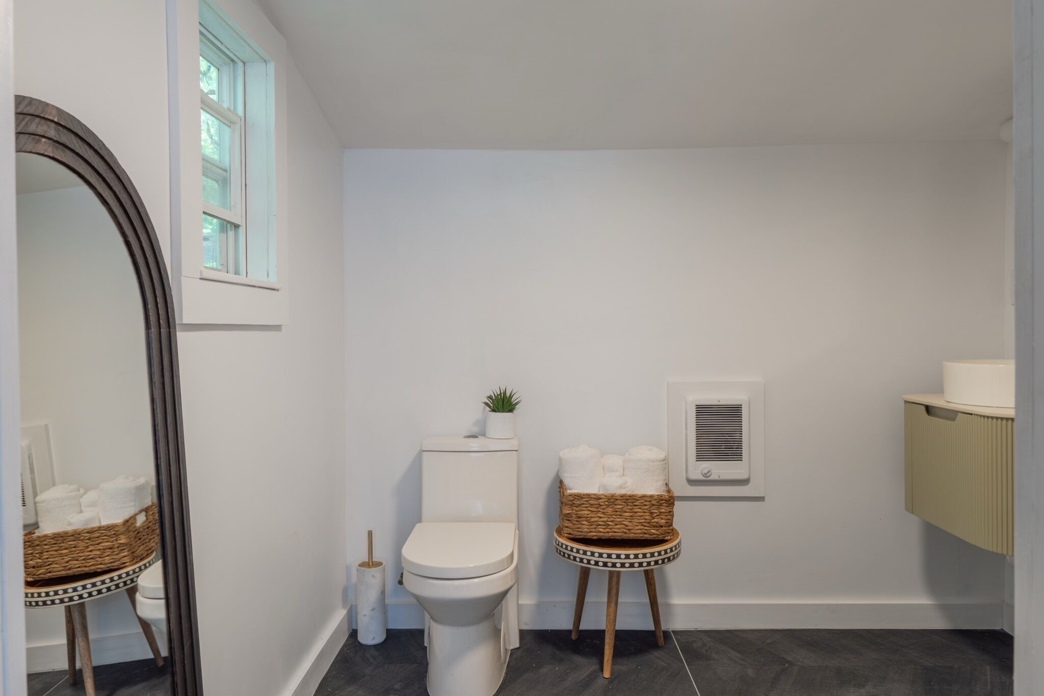 Ein Badezimmer mit Toilette, Bidet, Spiegel, Fenster und einer kleinen Pflanze.