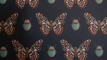 A pattern of stylized butterflies and beetles on a dark background.