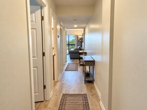 A hallway with a wooden floor, a rug, a sofa, and a table. - Oceanview 1BR Condo | Beach Resort | Sleeps 4 (Myrtle Beach)
