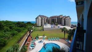 Um hotel com piscina, várias varandas e vista para o oceano.