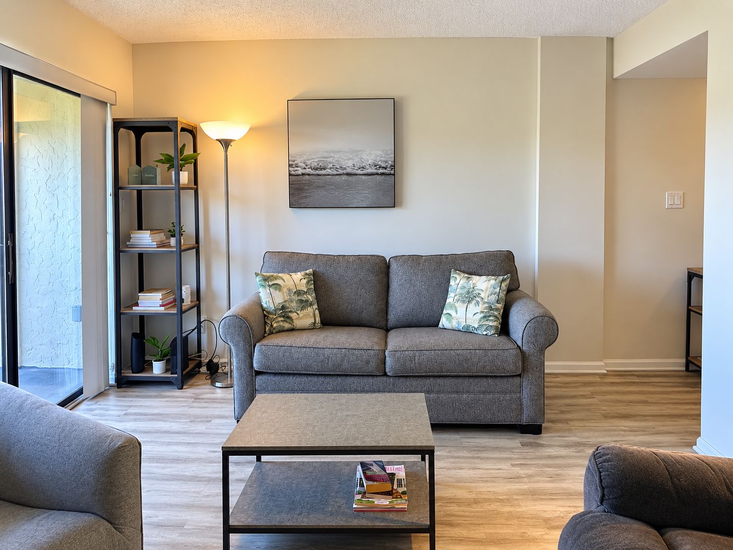 Ein Wohnzimmer mit grauem Sofa, einem Couchtisch und einem Bücherregal.