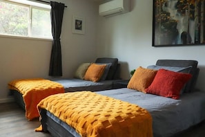 A room with two beds, a window with curtains, an air conditioner, and a painting on the wall. - Kalamoir Suite 1BR West Kelowna Escape Near Wineries, Trails & Beaches (West Kelowna)