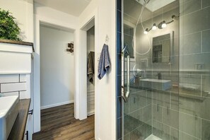 A modern bathroom with a glass shower enclosure, a white sink, and a wooden floor. - Kalamoir Suite 1BR West Kelowna Escape Near Wineries, Trails & Beaches (West Kelowna)