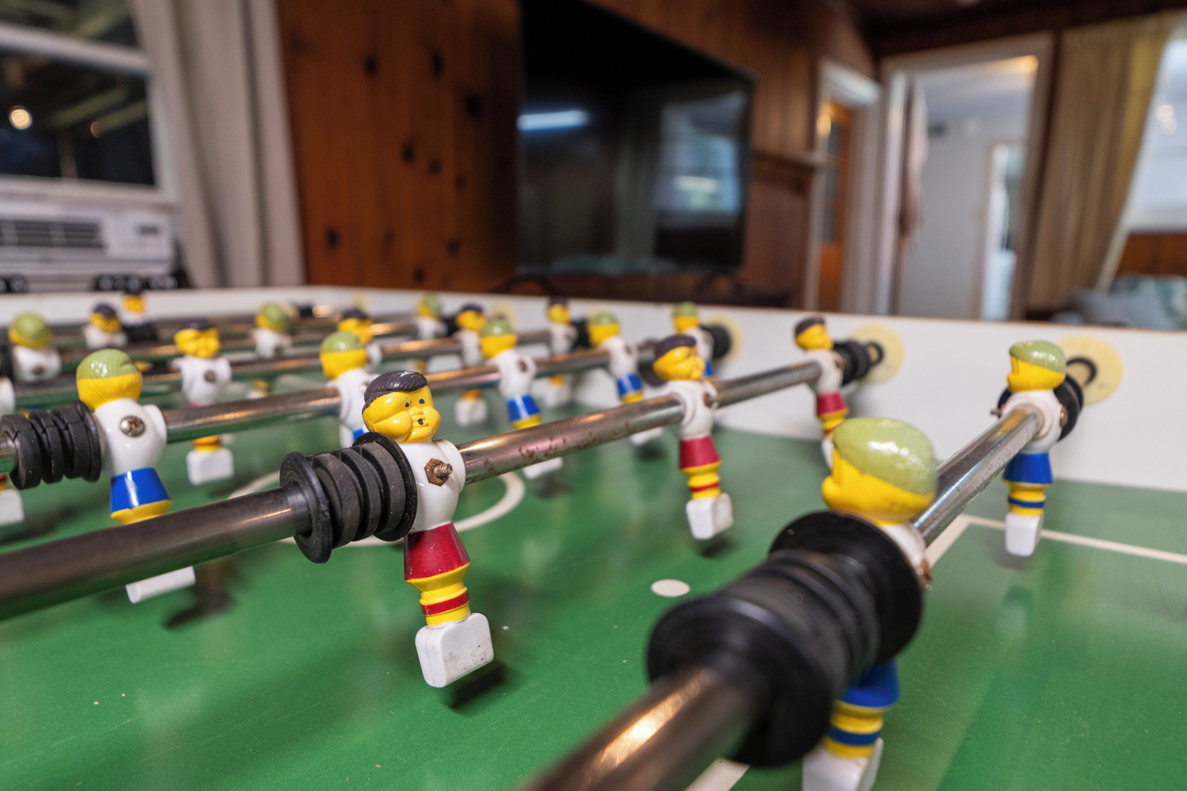 Een close-up van een tafelvoetbaltafel met verschillende spelersbeeldjes en staven.