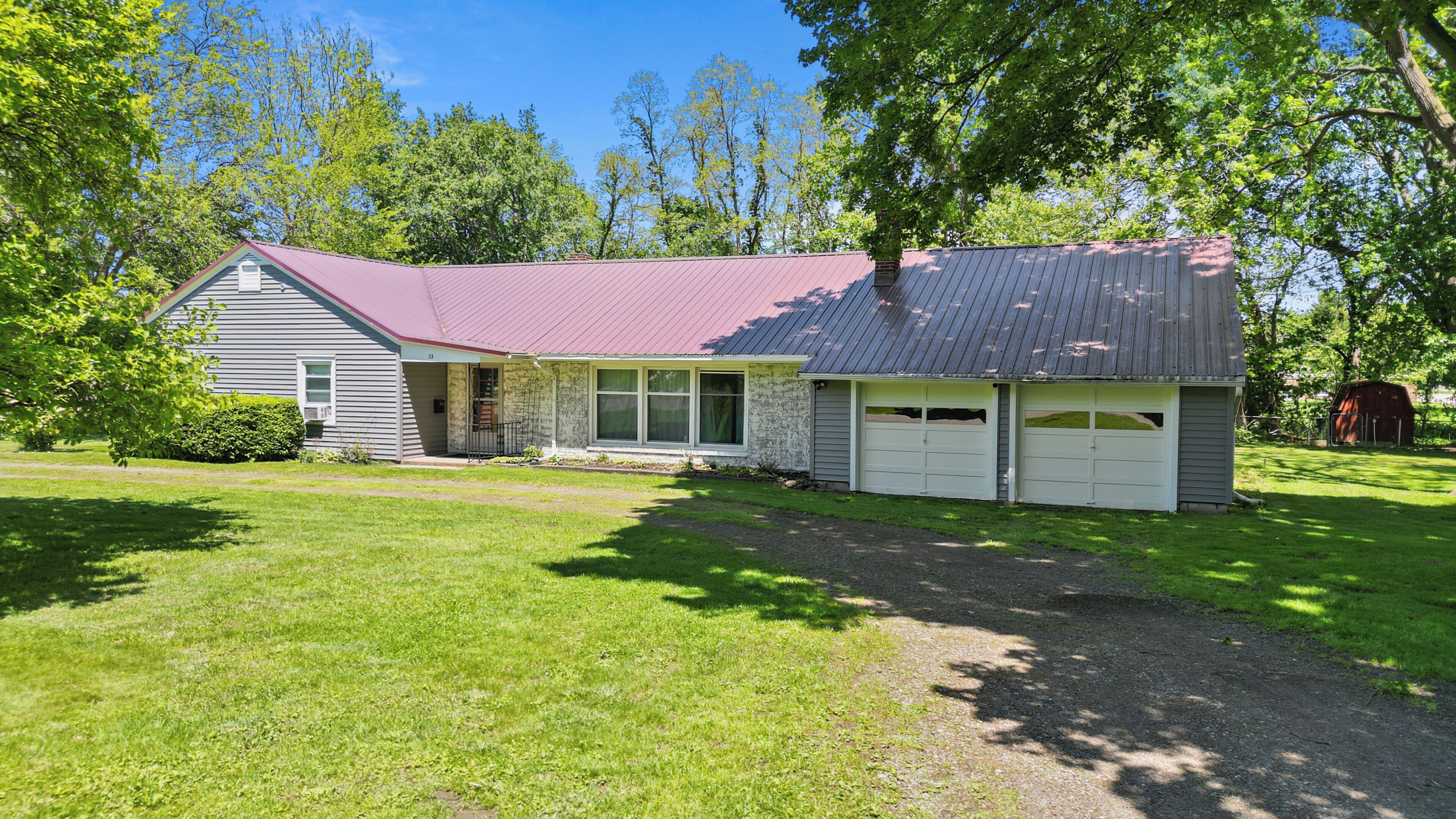 A two-story house with a red roof, a garage, and a well-maintained lawn.
