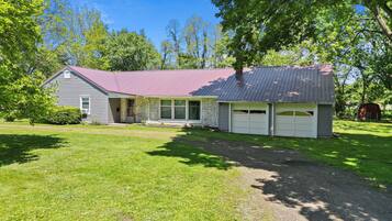 A two-story house with a red roof, a garage, and a well-maintained lawn.