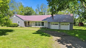 A two-story house with a red roof, a garage, and a well-maintained lawn. - Spacious 3BR Home with Pool Table & Patio Near Lake Erie (Westfield)