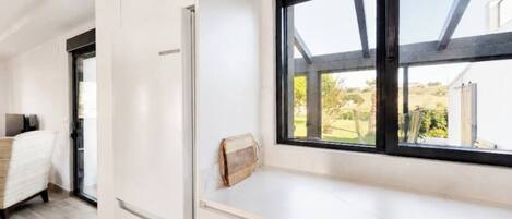 Une cuisine moderne dotée d’une fenêtre intégrée, de meubles blancs et offrant une vue sur l’extérieur.