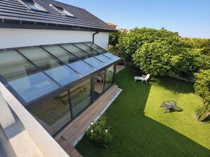 A modern house with a glass conservatory, a well-maintained lawn, and outdoor seating. - Casa Corbán by Wehomes (128) (Santander)