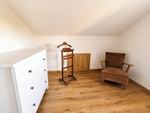 A room with a white dresser, a wooden chair, and a wooden wardrobe. - Casa Corbán by Wehomes (128) (Santander)