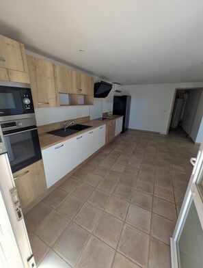 A kitchen with wooden cabinets, a black refrigerator, and a tiled floor. - Horizon Pond Villa with Pool and Panoramic View (Rognac)