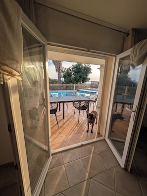 A glass door leading to an outdoor patio with a pool, chairs, and a dog. - Horizon Pond Villa with Pool and Panoramic View (Rognac)