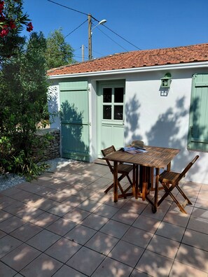 A patio with a table and chairs, a green door, and a white wall. - Our house, just 4 minutes from the beaches (La Guérinière)