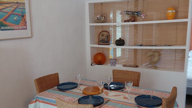 A dining area with a table set for four, wicker chairs, and a hanging light fixture. - Our house, just 4 minutes from the beaches (La Guérinière)