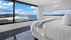 Una camera d'albergo con un'ampia finestra vista mare e colline lontane.