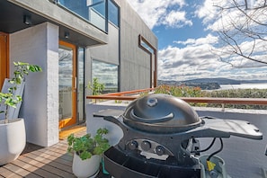 Une maison moderne dotée d’un balcon, d’un barbecue et de plantes en pot.