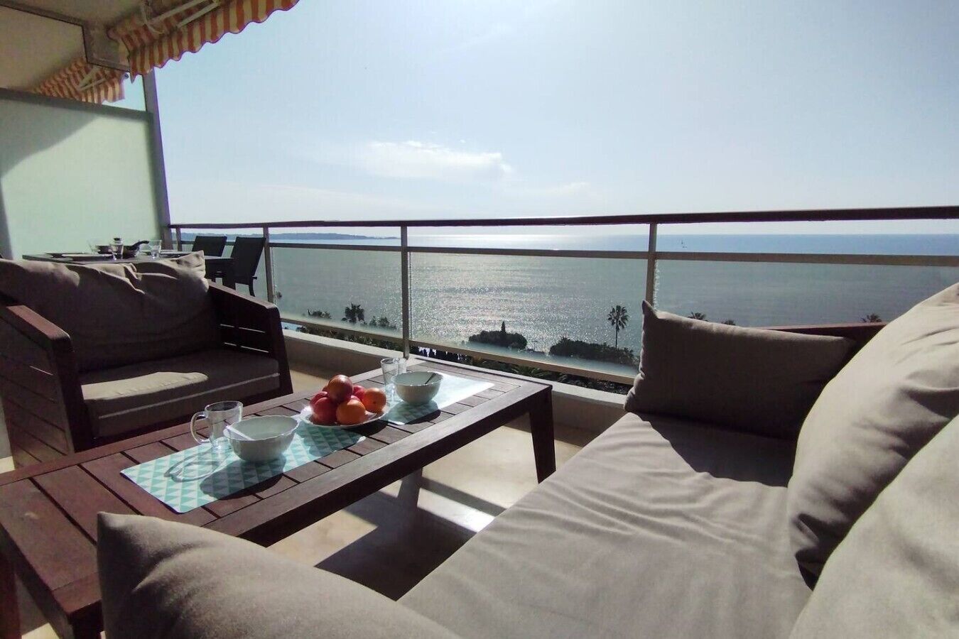Un balcon avec vue sur la mer, aménagé avec un canapé, une table et une chaise.